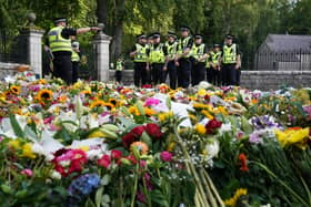 Police officers arrive at the gates of Balmoral in Scotland where flowers and tributes have been laid by members of the public following the death of Queen Elizabeth II. The Queen's coffin will be transported on a six-hour journey from Balmoral to the Palace of Holyroodhouse in Edinburgh, where it will lie at rest. Picture date: Sunday September 11, 2022.