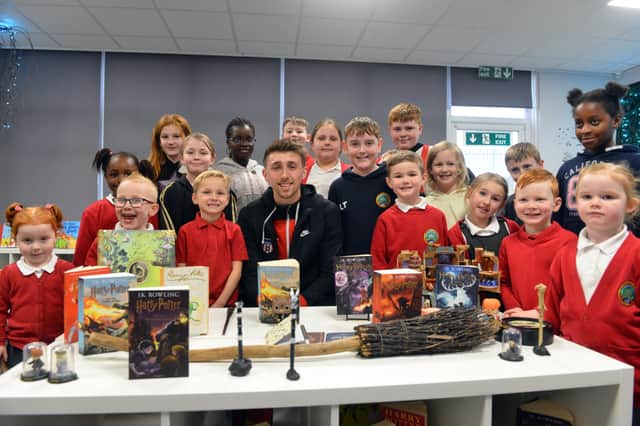 SAFC midfielder Dan Neil joins children in the school's new library.