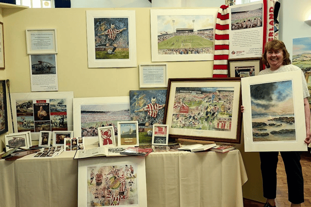 Janet alongside the her Dad's artworks from Vaux Breweries and Sunderland AFC