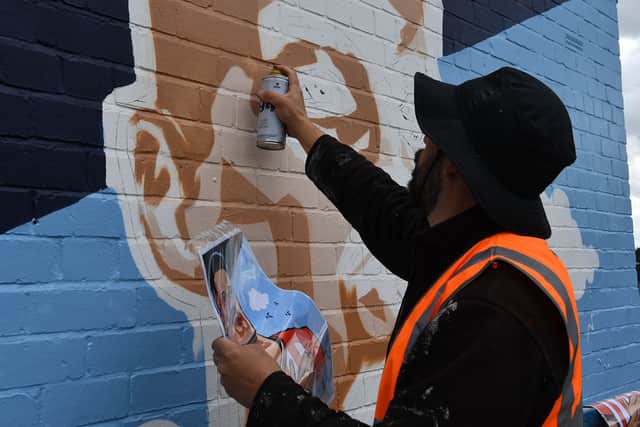 A spray paint artist working on bringing Kathryn's design to life.