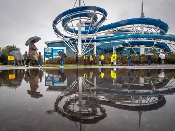 People queue in the rain at a Smart Covid-19 testing centre outside the Splash World swimming centre in Southport