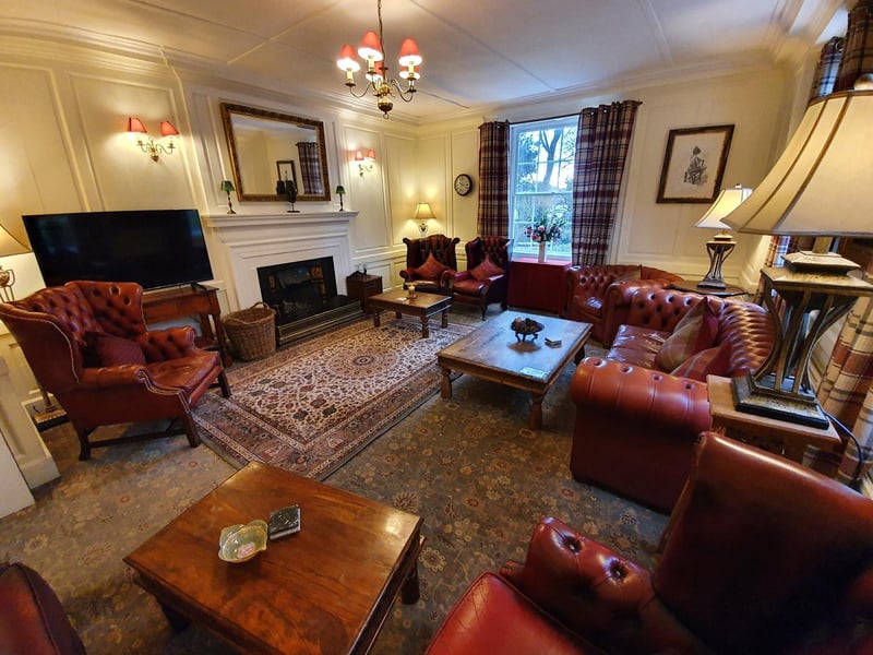 One of the hotel's loungers with luxurious red leather seating and an inviting open fire.