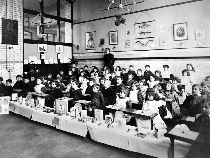 A class of children about to have a craft lesson at Darley Street School. Each child has a small ball of clay to model with. There is a 'nature table' in front of the class.