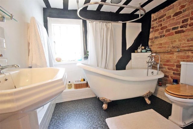 The stylish family bathroom features exposed brickwork, beams and a clawfoot bath