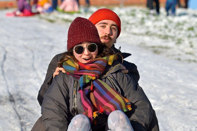 A happy couple enjoy a slide in the snow covered Brooke Park on Saturday afternoon last. Photo: George Sweeney / Derry Journal.  DER2104GS – 010