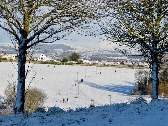 People walk in the sunshine and in a picturesque snow covered Creggan Burn on Saturday morning last. Photo: George Sweeney / Derry Journal.  DER2104GS – 015