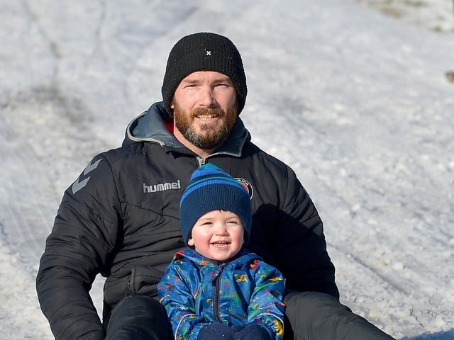 James O’Reilly and his dad, James, slide in a snow covered Brooke Park on Saturday afternoon last. Photo: George Sweeney / Derry Journal.  DER2104GS – 012