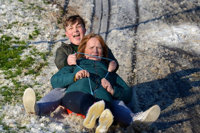 Cian Tierney and his grandmother Mary enjoy a slide in a snow covered Brooke Park on Saturday afternoon last. Photo: George Sweeney / Derry Journal.  DER2104GS – 026