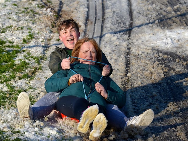 Cian Tierney and his grandmother Mary enjoy a slide in a snow covered Brooke Park on Saturday afternoon last. Photo: George Sweeney / Derry Journal.  DER2104GS – 026