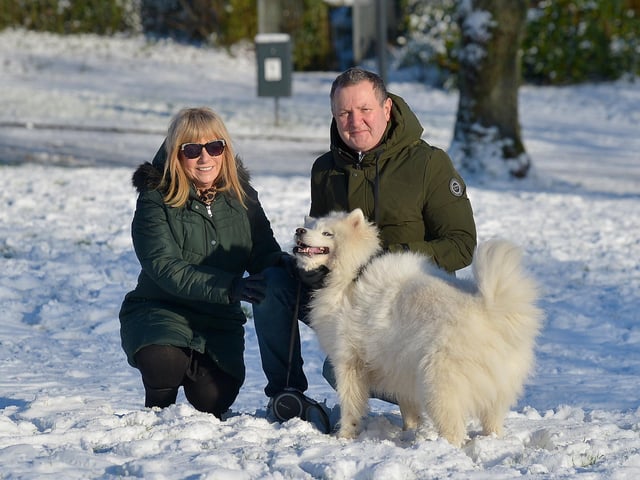 Joan and Terry Casey pictured with their dog Sasha in a snow covered Brooke Park on Saturday afternoon last. Photo: George Sweeney / Derry Journal. DER2104GS – 031