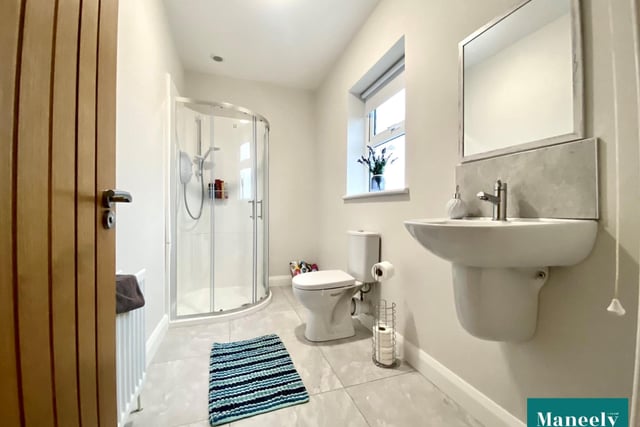 The modern en suite features a white suite low flush WC, wall hung wash hand basin and shower pod with 'Mira' electric shower.