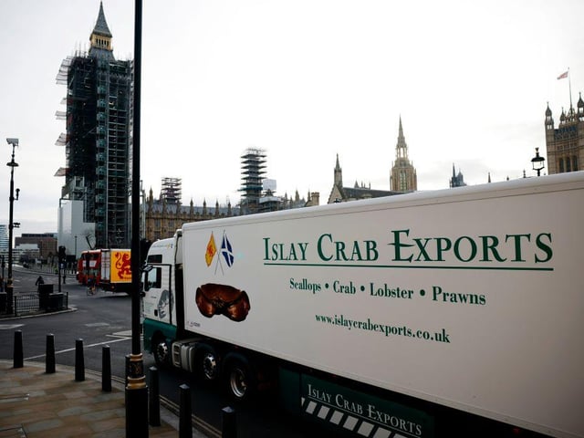 Lorries from Scottish seafood companies drive past the Houses of Parliament. (Photo by Tolga Akmen / AFP)