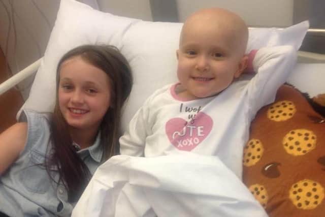Brave Daisy in her hospital bed with her big sister Poppy by her side.