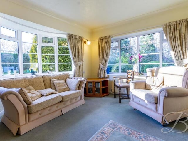 Another look at the living room and its magnificent bay windows, which let in a wealth of light.  The floor is carpeted, and there's a central heating radiator.