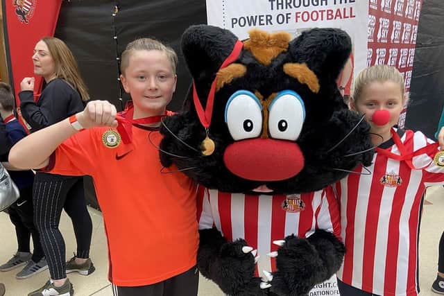 Twins Finnley and Kiera Wilson, both 11, with their medals, alongside Samson the cat.