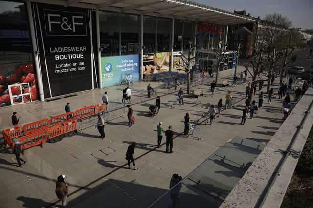 FILE - In this Friday, April 10, 2020 file photo people observe social distancing in an attempt to stop the spread of coronavirus by standing behind tape lines as they queue up to shop outside a branch of the Tesco supermarket chain in west London. (AP Photo/Matt Dunham, File)