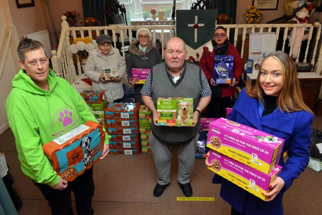Steve Hutchinson hands over the Christmas donations to Happier Days for Strays' Lisa Scott and Pawz for Thought's Jessica Appleby (right), watched by members of the congregation