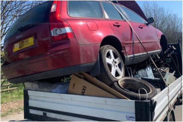 A driver who was pulling a trailer that had a car precariously perched on top of scrap metal and not secured in place.