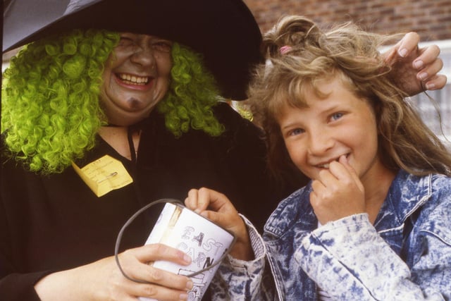 Wicked witch Pat Burr menaces nine year old Lisa Johnson into parting with her pocket money, but it's all in a good cause at the East End Carnival in 1988.