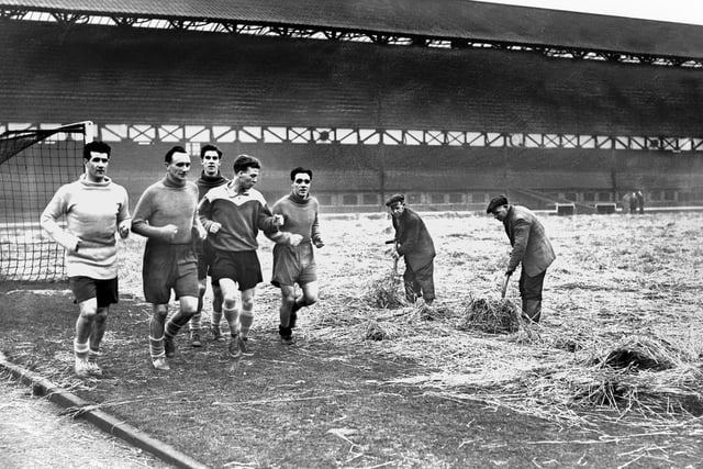 Ground staff tend to the Roker Park pitch as Sunderland players left to right George Aiken, Arthur Wright, Harry Kirtley, Billy Bingham, John McSeveney do laps. 