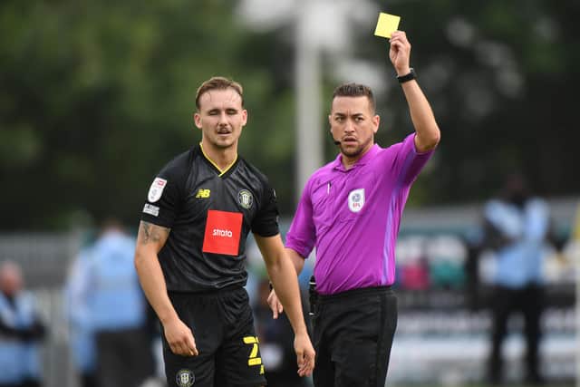 Referee Paul Howard shows a yellow card to Jack Diamond of Harrogate Town during the Sky Bet League Two match between Mansfield Town and Harrogate Town at One Call Stadium.