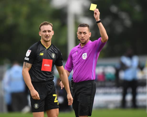 Referee Paul Howard shows a yellow card to Jack Diamond of Harrogate Town during the Sky Bet League Two match between Mansfield Town and Harrogate Town at One Call Stadium.