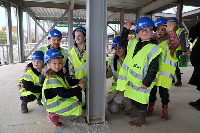 Children from Sunningdale School sign the steel girders which are providing the framework for their new school.
