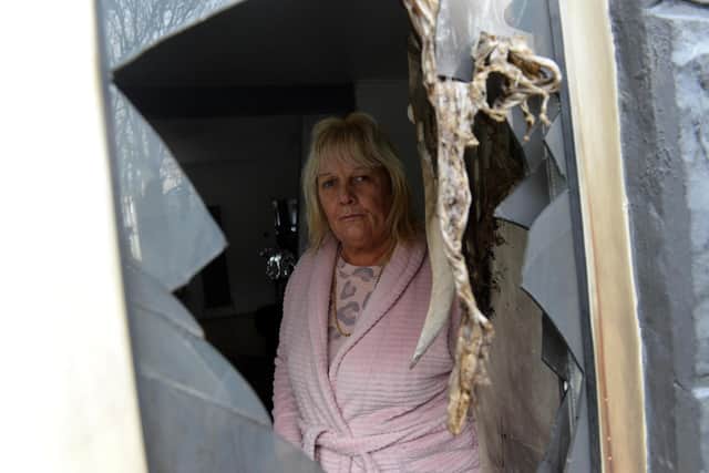 Tracy Husband looking through the smashed window of her Houghton home.
