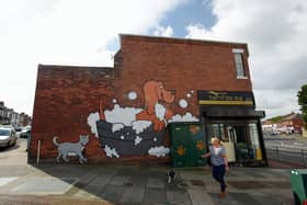 A dog walker passes by the controversial mural in Durham Road