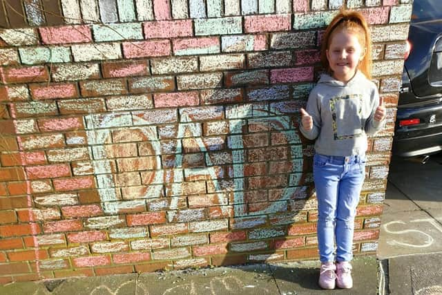 Six year-old Rhed Hendry with some of the artwork she created to honour her dad.