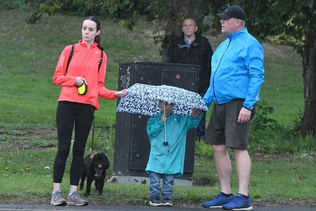 A family at Newbottle takes shelter against the rain as they wait the Tour of Britain cyclists.