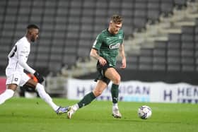 Dan Scarr of Plymouth Argyle moves with the ball away from Mo Eisa of Milton Keynes Dons.