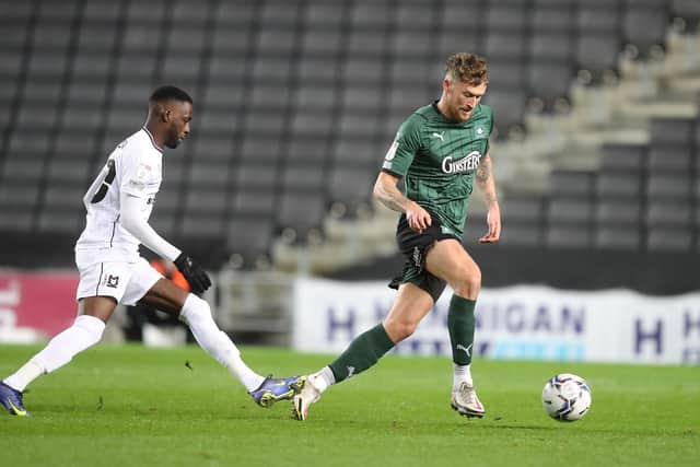 Dan Scarr of Plymouth Argyle moves with the ball away from Mo Eisa of Milton Keynes Dons.