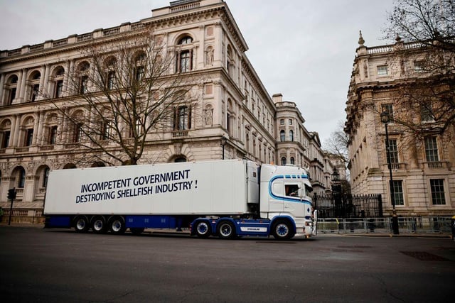 A truck drives past Downing Street with a message that reads "Incompetent government destroying shellfish industry". More than 10 of the haulage vehicles were photographed parked near Downing Street and Whitehall. (Photo by Tolga Akmen / AFP)