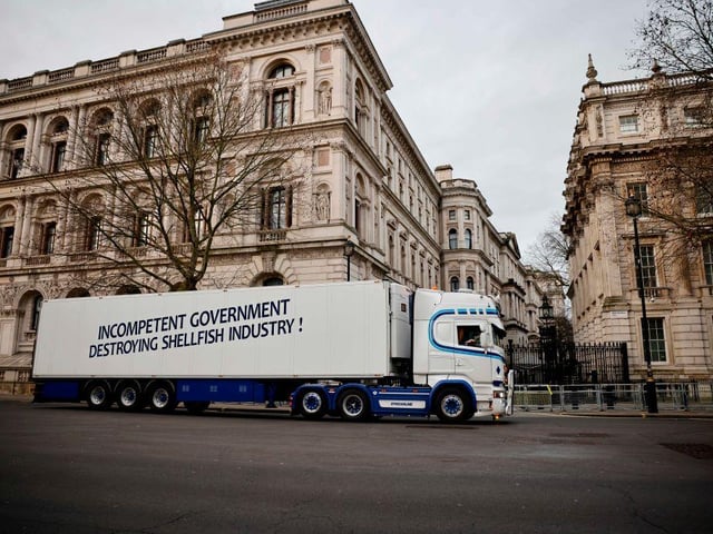 A truck drives past Downing Street with a message that reads "Incompetent government destroying shellfish industry". More than 10 of the haulage vehicles were photographed parked near Downing Street and Whitehall. (Photo by Tolga Akmen / AFP)
