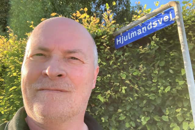 Søren Plovgaard next to an Assens street sign which has the name of the Denmark coach.