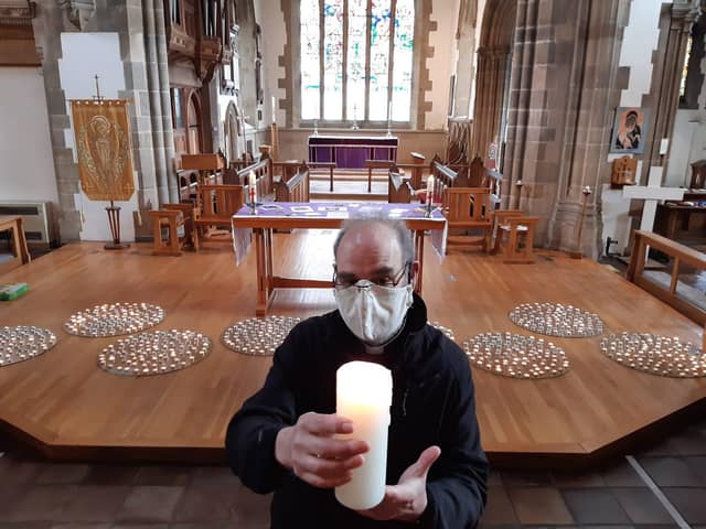 Provost of Sunderland Minster, the Reverend Canon Stuart Bain lifts a candle lit as part of the display set up to mark one year on since coronavirus lockdowns began.