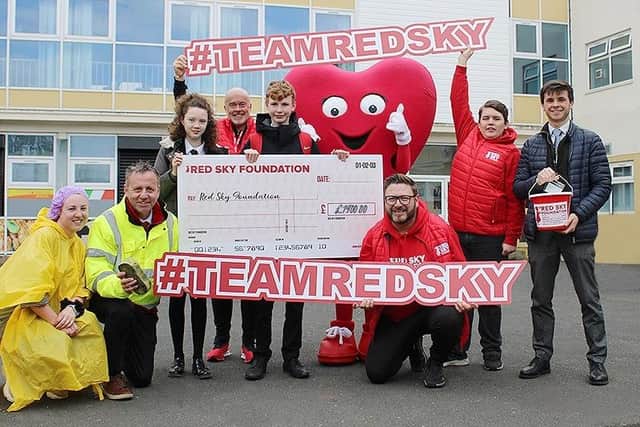 Staff and pupils present a cheque to the Red Sky Foundation founder Sergio Petrucci (front centre).