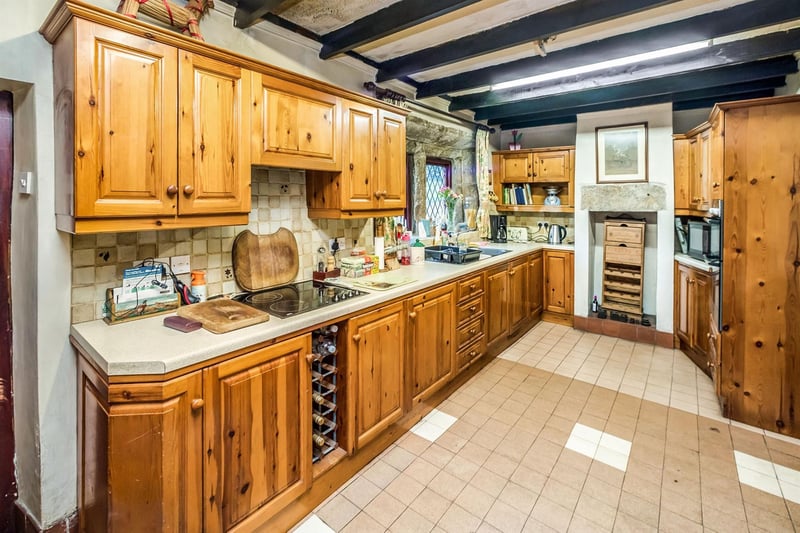 Farmhouse-style kitchen with a beamed ceiling, tiled floor and tiled splashbacks.