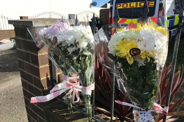 Flowers have been tied to the fence outside the garage where human remains were found following a fire.
