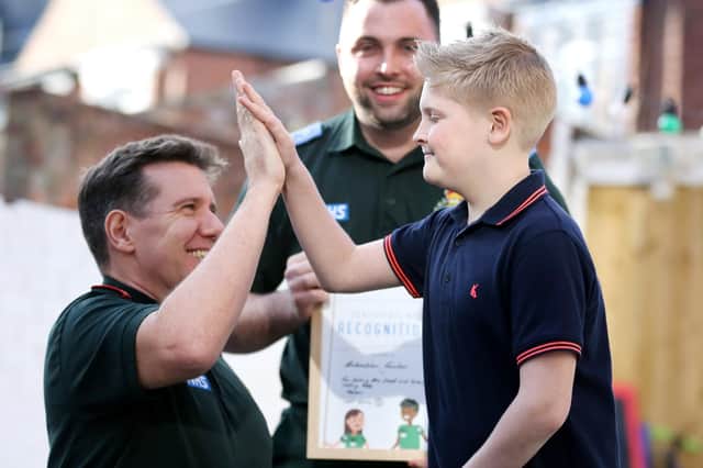 Sebastian Fowler high fives NEAS paramedic Andy Wilson as he congratulates him for his calm actions following his mother's fit.