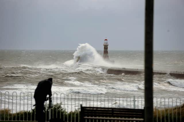 Photographers on the seafront capturing the stormy seas.