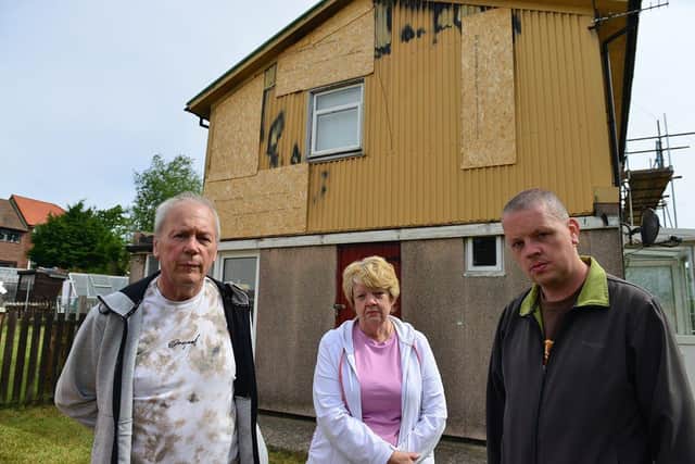William and Fiona with their son William Holland (right) outside of their damaged home.