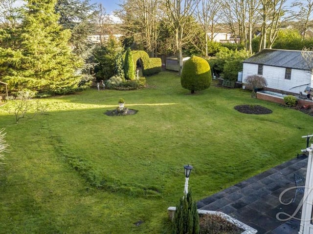 The back garden in all its glory, captured by this drone shot. As well as the extensive lawn there are mature shrubs and trees.