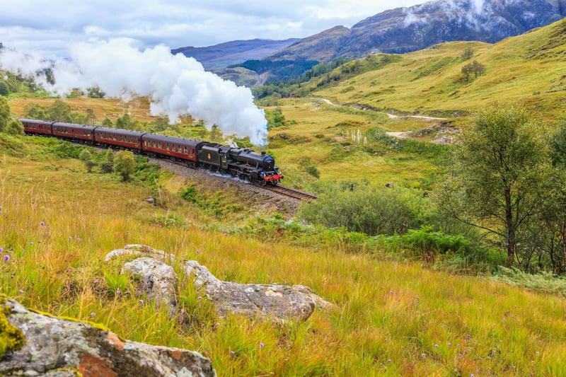 A steam train rolling through the Scottish Highlands.