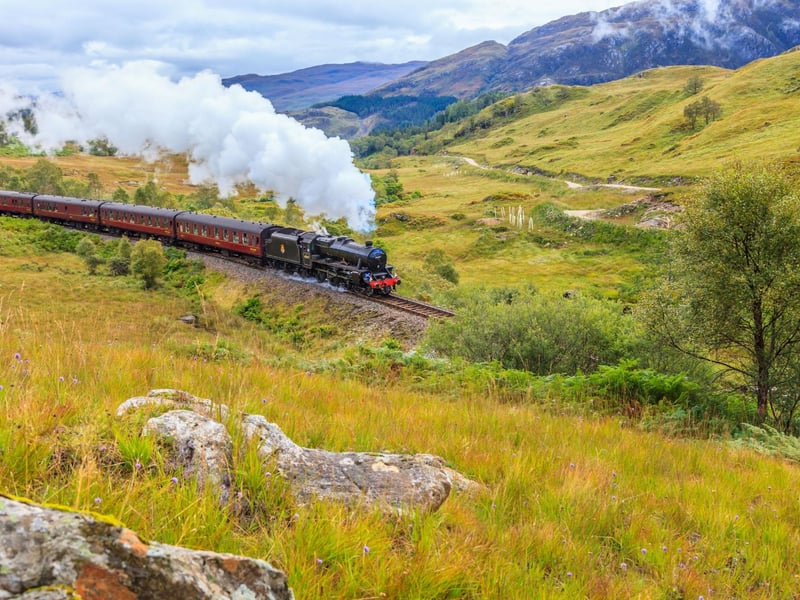 A steam train rolling through the Scottish Highlands.