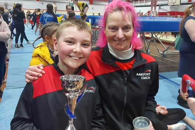 Finley Jones, 11, holding his trampoline trophy alongside one his coaches from AAA Sports.
