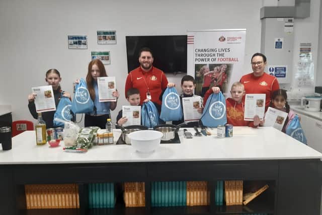 Foundation of Light staff Dan Coyne and Lucy Todhunter with children Alfie, 9, Leon, 12, Kia, 11, Mia, 13, Mehrsa, 8, and Imogen, 11, all holding their recipe cards and bags.