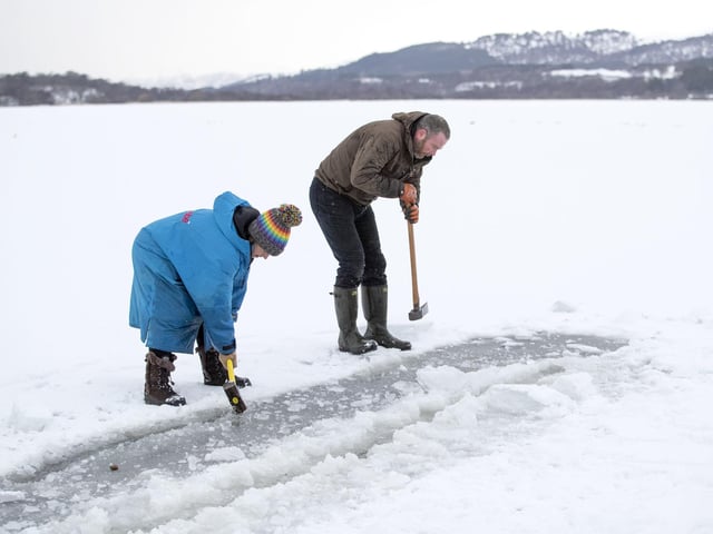 Al and Alice Goodridge, from Newtonmore, use a sledgehammer and an axe to create a channel in the ice in Loch Insh, in the Cairngorms National Park, for Alice to swim in.