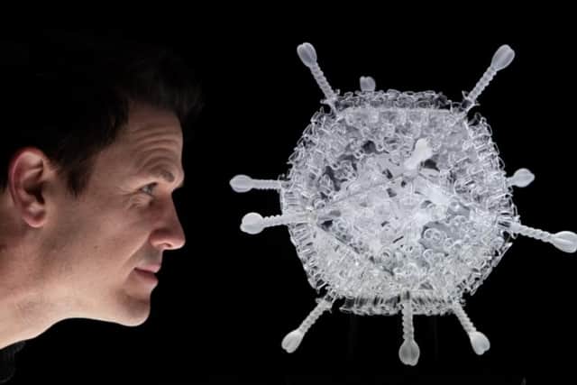 Luke Jerram looks at his glass sculpture of the Oxford/AstraZeneca vaccine, made to mark the ten millionth vaccination in the UK.